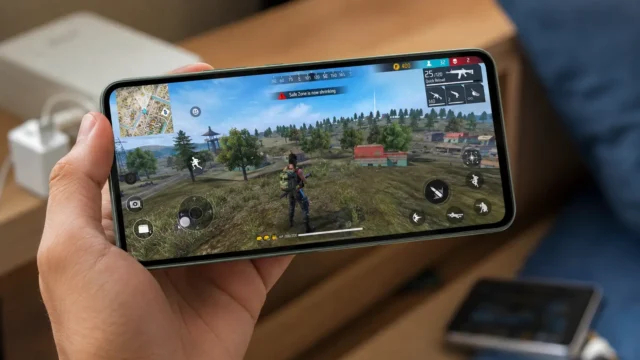 Smartphone Poco em modo horizontal rodando jogo, segurado por uma mão em ambiente doméstico